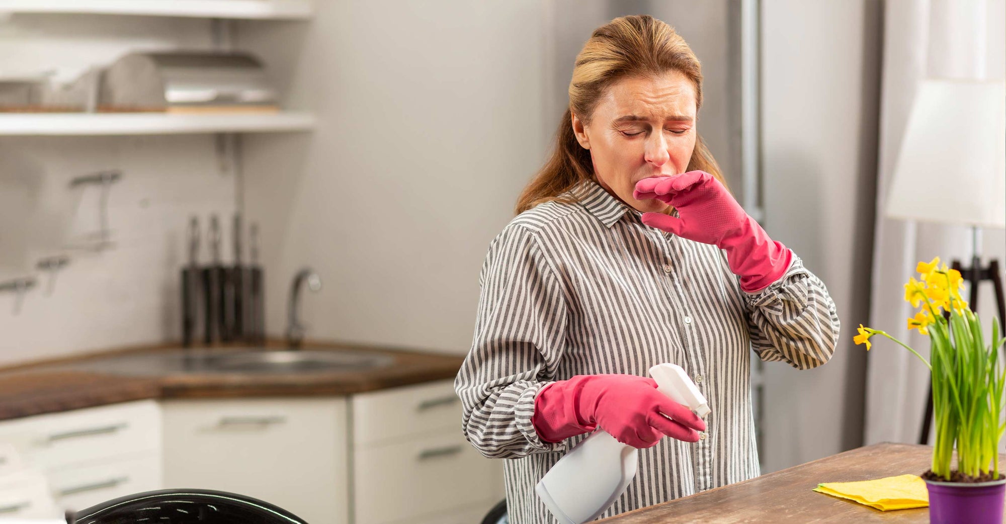 Woman in kitchen sneezing