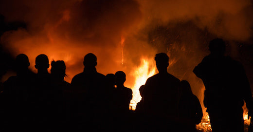 Crowd standing in front of smoke and flames