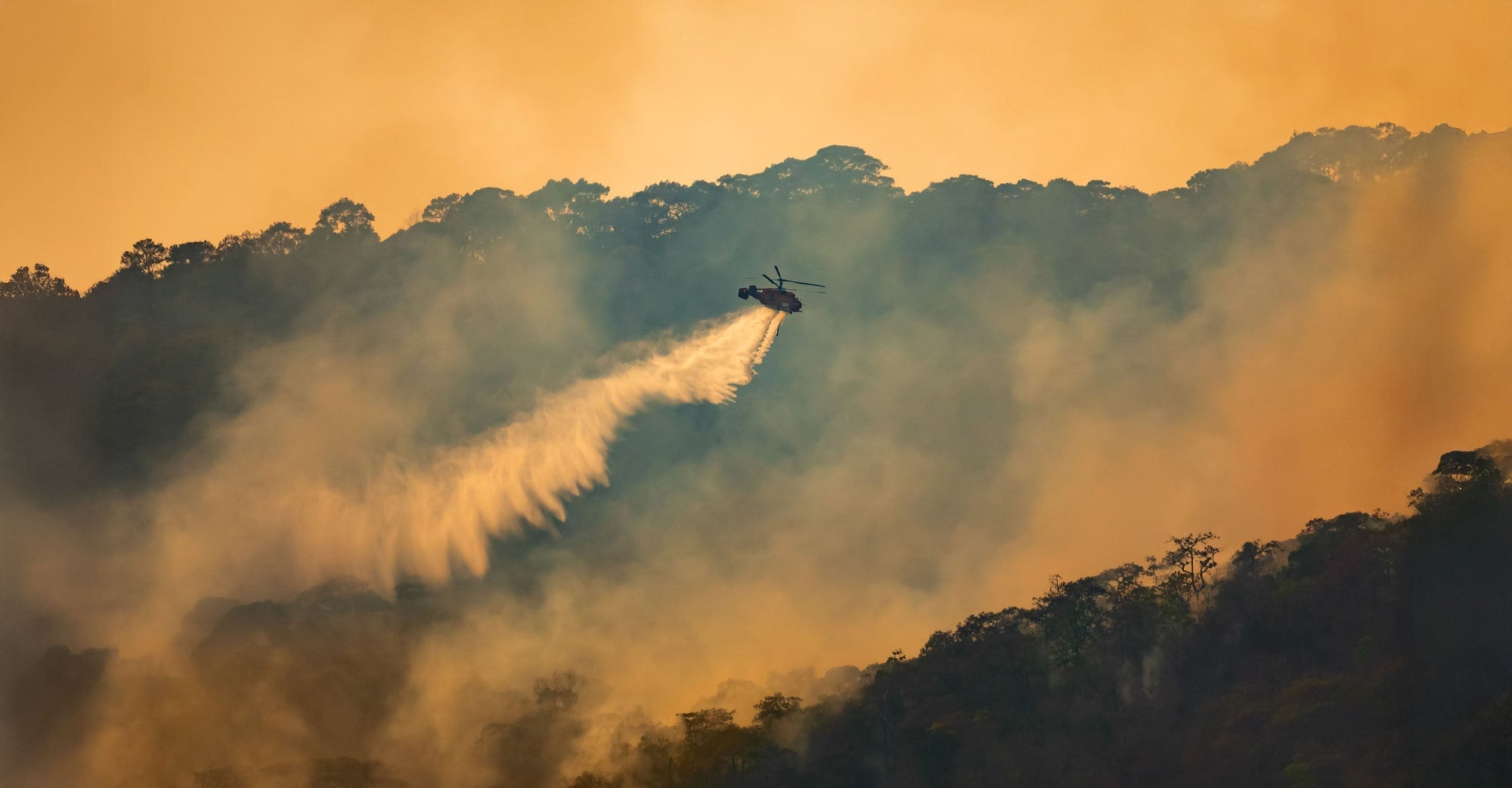 Helicopter flying over smoke shrouded mountain